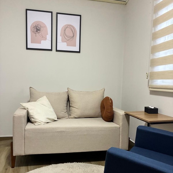 Sala de espera com sofá claro e quadros na parede